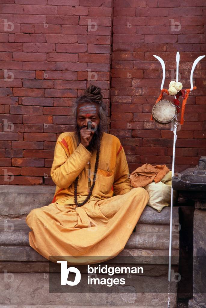 Nepal: A sadhu with his trident and smoking hashish, Kathmandu