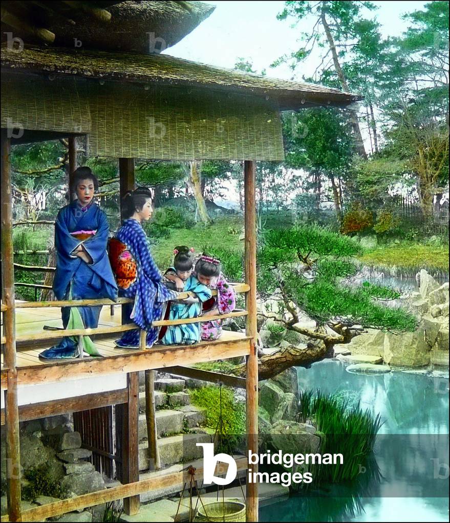 Japan: Two geisha with two little girls in a pavilion overlooking an ornamental pond, c.1900