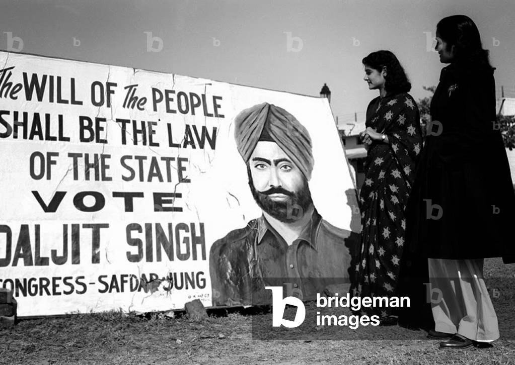 India: First Lok Sabha general election, Delhi, January 1952. Women voters reading an election poster for a Congress Party candidate