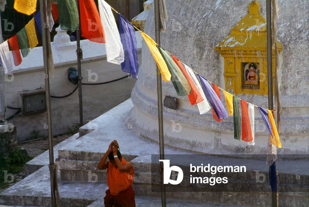 Nepal: A monk prays next to a small stupa at Bodhnath (Boudhanath), Kathmandu
