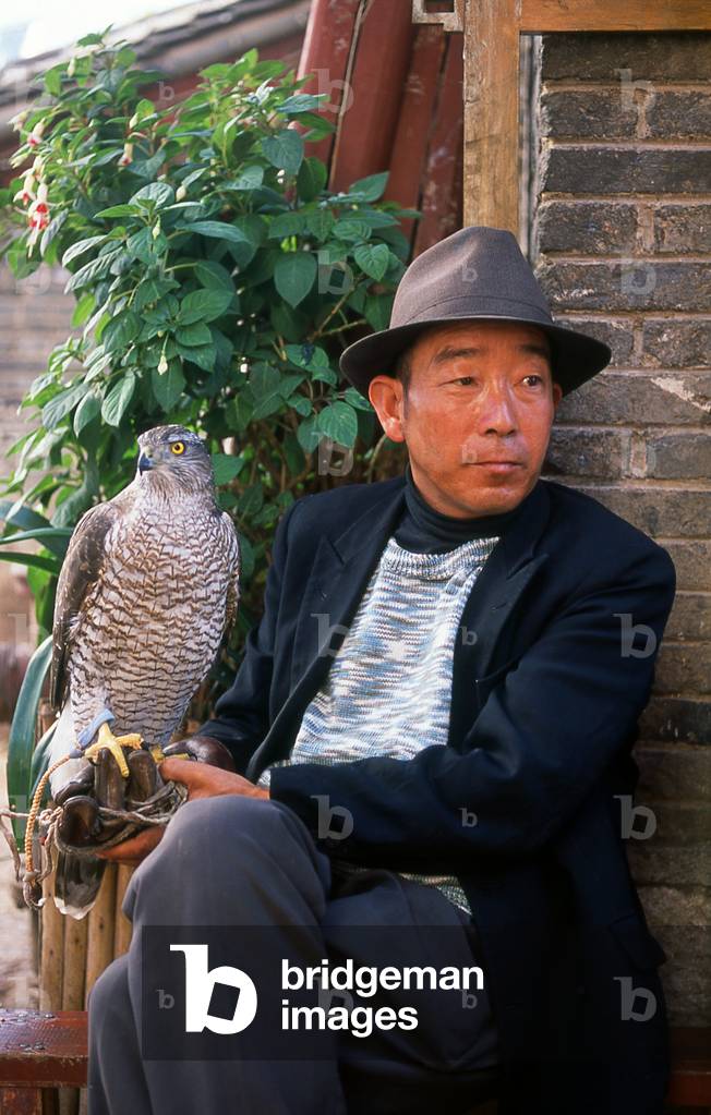 China: Naxi man with his pet goshawk in Lijiang Old Town, Yunnan Province