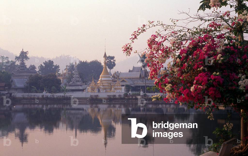 Thailand: Wat Jong Kham, framed by multi-coloured bougainvillaea, reflected in the waters of Lake Jong Kham, Mae Hong Son, northern Thailand