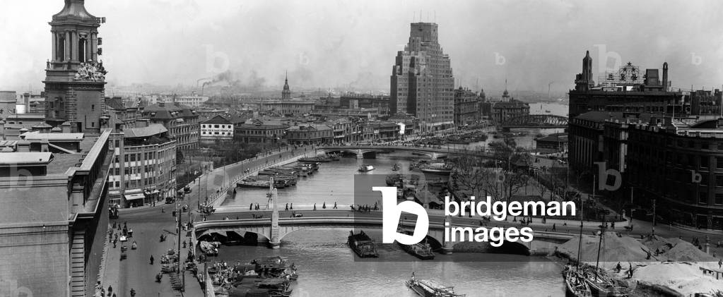China: Shanghai, looking south down Suzhou Creek past the Waibaidu Bridge to the Huangpu River. Smoking chimneys and the bulk of the Broadway Mansions building in distance. c. 1935
