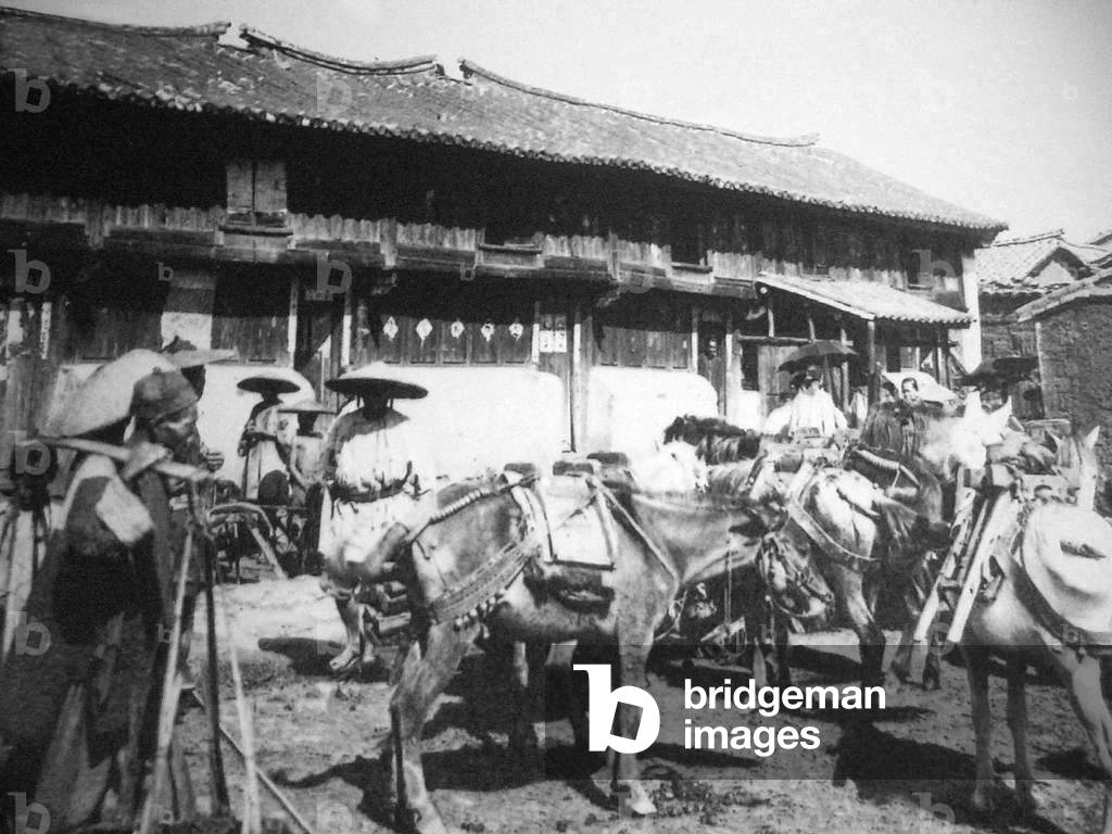 China: A Hui Muslim mule caravan passing through a village in western Yunnan c. 1905