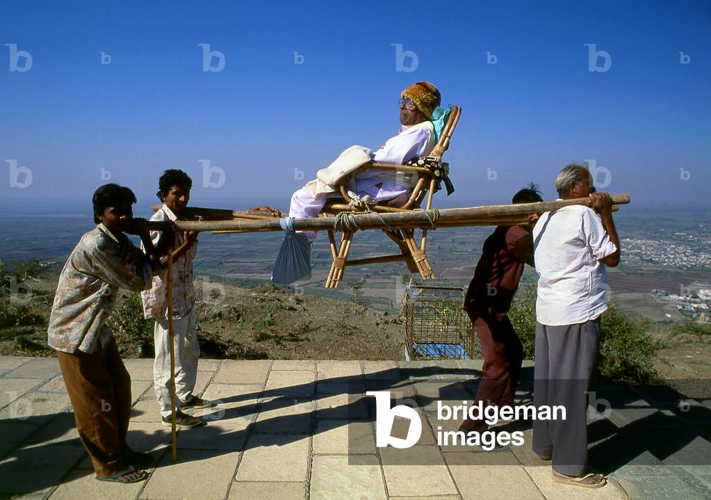 India: A pilgrim being carried in a sedan chair up to the holy Jain Palitana temples (11th to 16th Century CE) in the Shatrunjaya Hills, Gujarat (2004)