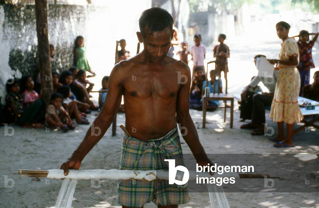 Maldives: Preparing a traditional loom for weaving a 