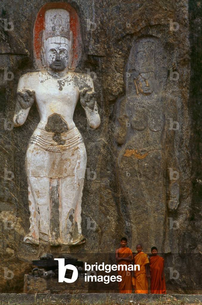 Sri Sri Lanka: monks in front of 1000 year old carved stone figures, Sri Lanka (photo): Young Buddhist monks in front of 1000 year old carved stone figures representing the Avalokitesvara (left) and his consort Tara (right), Buduruvagala (photo)