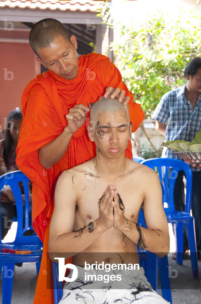 Thailand: Thai Buddhist ordination ceremony, Chiang Mai. Firstly the nakor monk-to-be has his head shaved. The complete shaving of the head and eyebrows is then undertaken by a monk