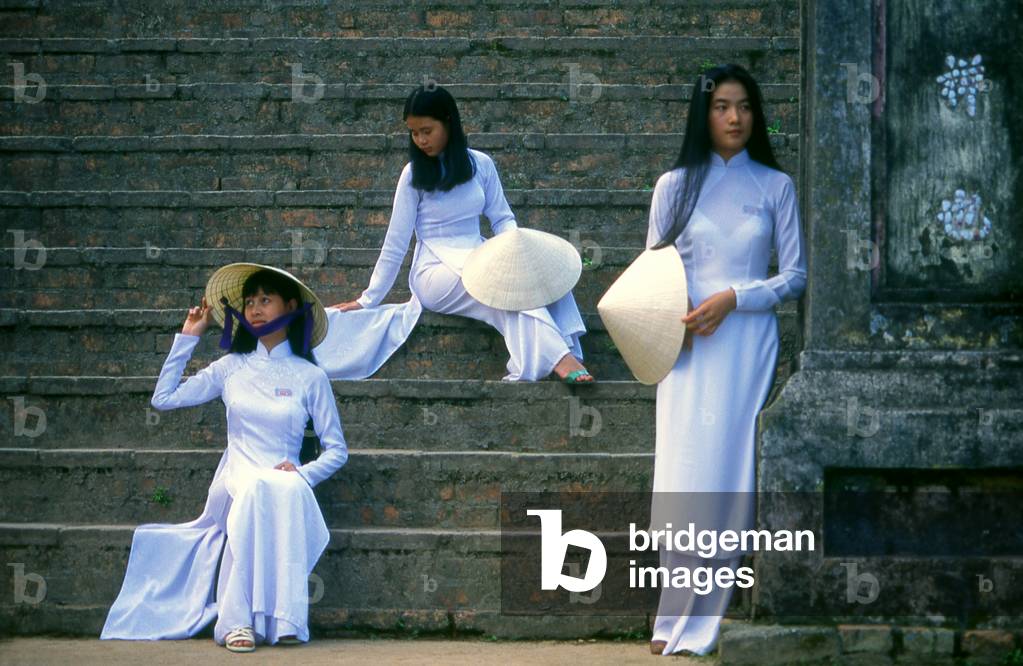 Vietnam: Students in traditional Vietnamese ao dai ('long dress') and non la (conical hat) at the Thien Mu Pagoda with Elvis Phuong, Hue