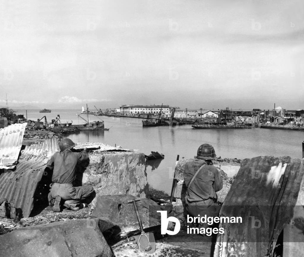 Philippines / USA: American soldiers in a partially destroyed Japanese fortification keep their rifles trained on Japanese positions across the Pasig River during the Battle of Manila, 27 February 1945