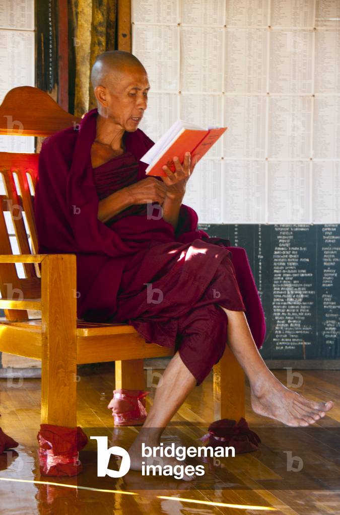 Burma-Myanmar: A senior Buddhist monk sits in front of lists of temple donors from all over the world at the Shwe Yan Pyay Monastery, Nyaung Shwe, Shan State