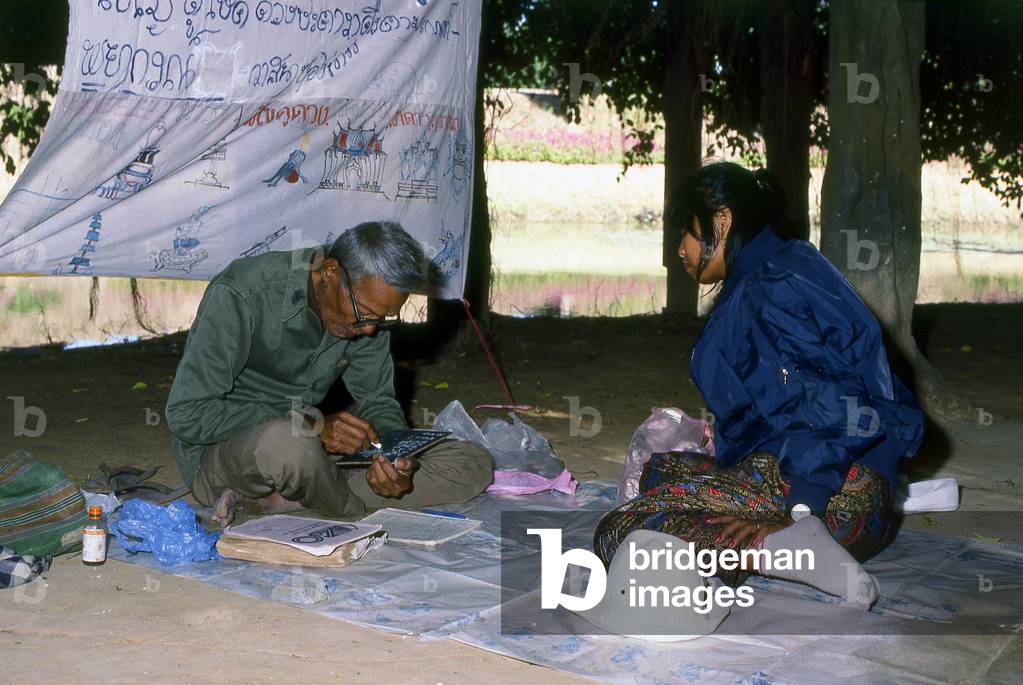 Thailand: Fortune teller beneath the giant banyan tree near Prasat Hin Phimai, Nakhon Ratchasima Province. Phimai dates from the 11th and 12th century and was an important Khmer Buddhist temple and town in the Khmer empire