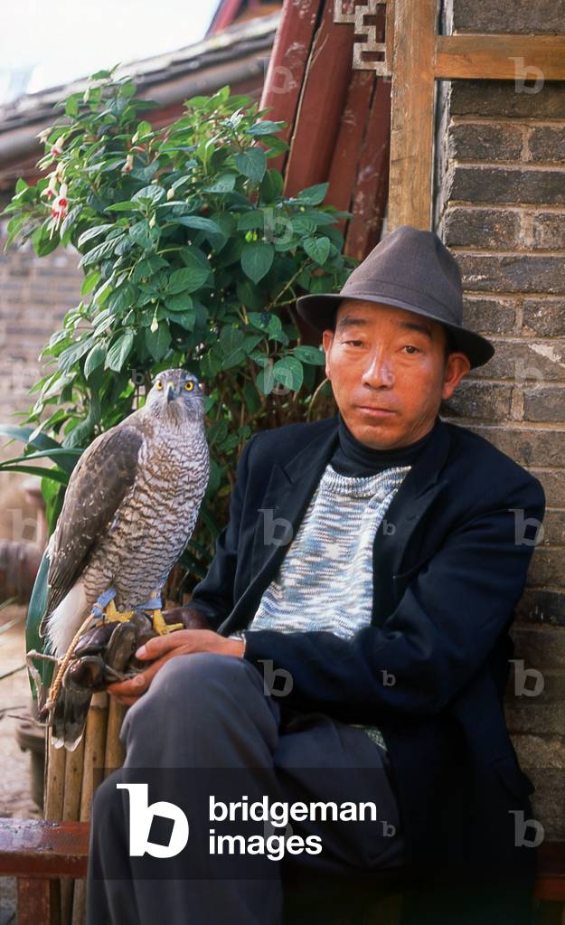China: Naxi man with his pet goshawk in Lijiang Old Town, Yunnan Province