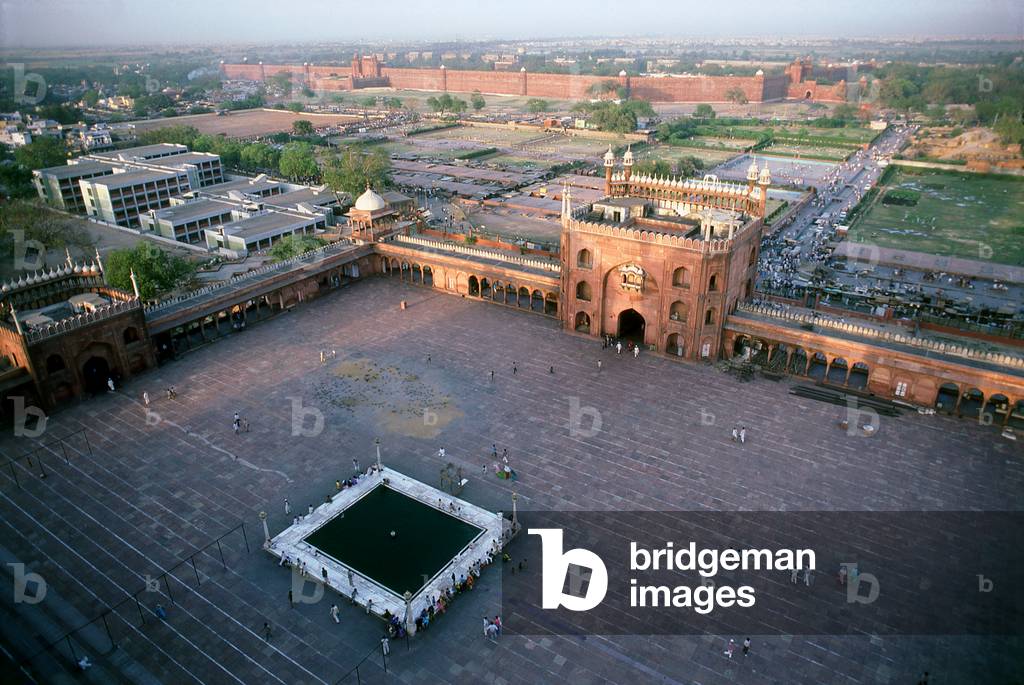 India: Late afternoon in the giant courtyard at the Jama Masjid, India's largest mosque with Old Delhi's Red Fort in the background, Delhi