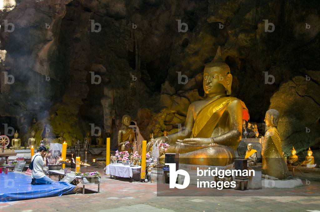 Thailand: Worshipper in front of a large seated Buddha inside Tham Khao Luang, Phetchaburi