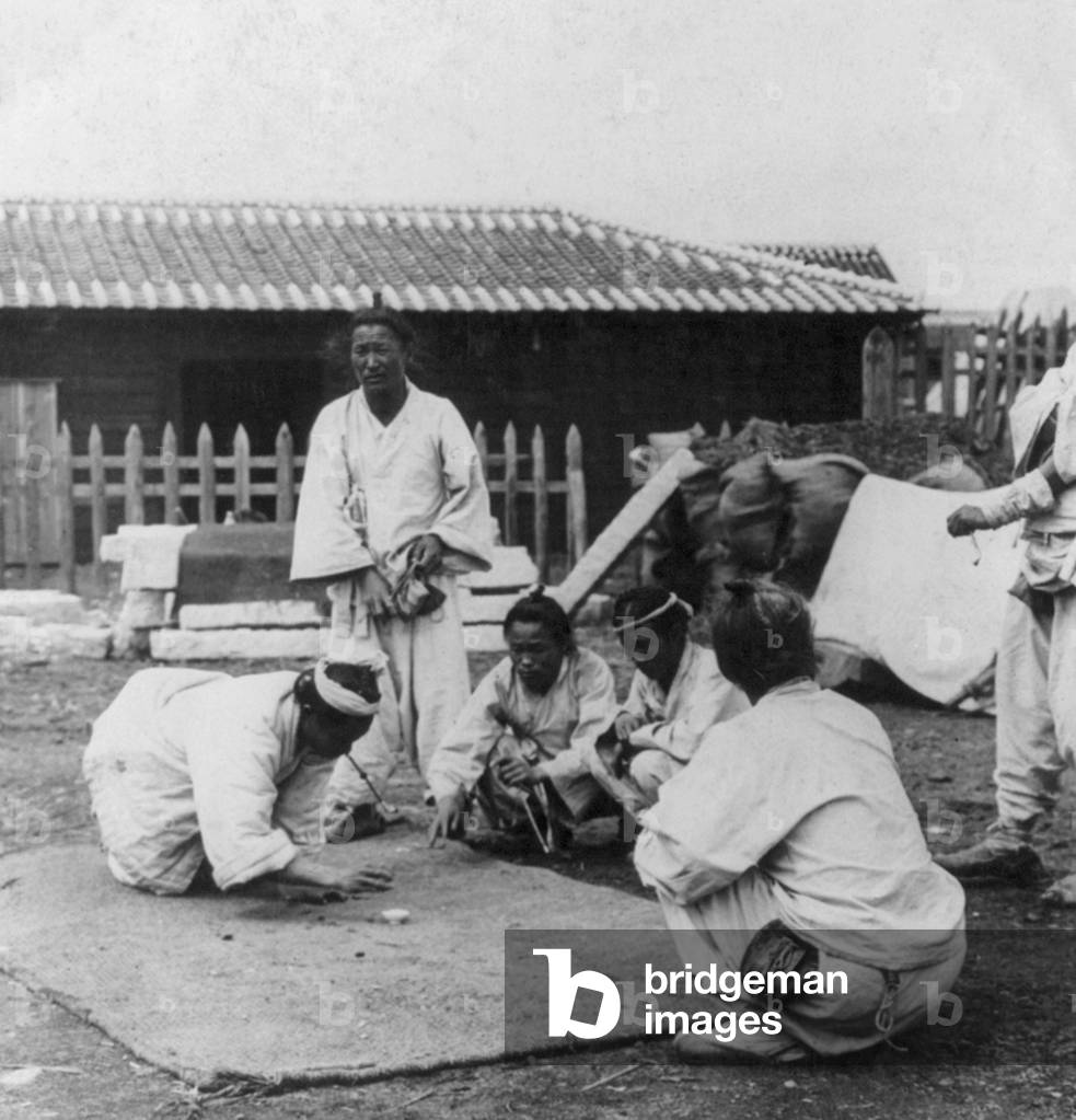 Korea: A group of Korean men gambling in the street, Seoul, early 20th century