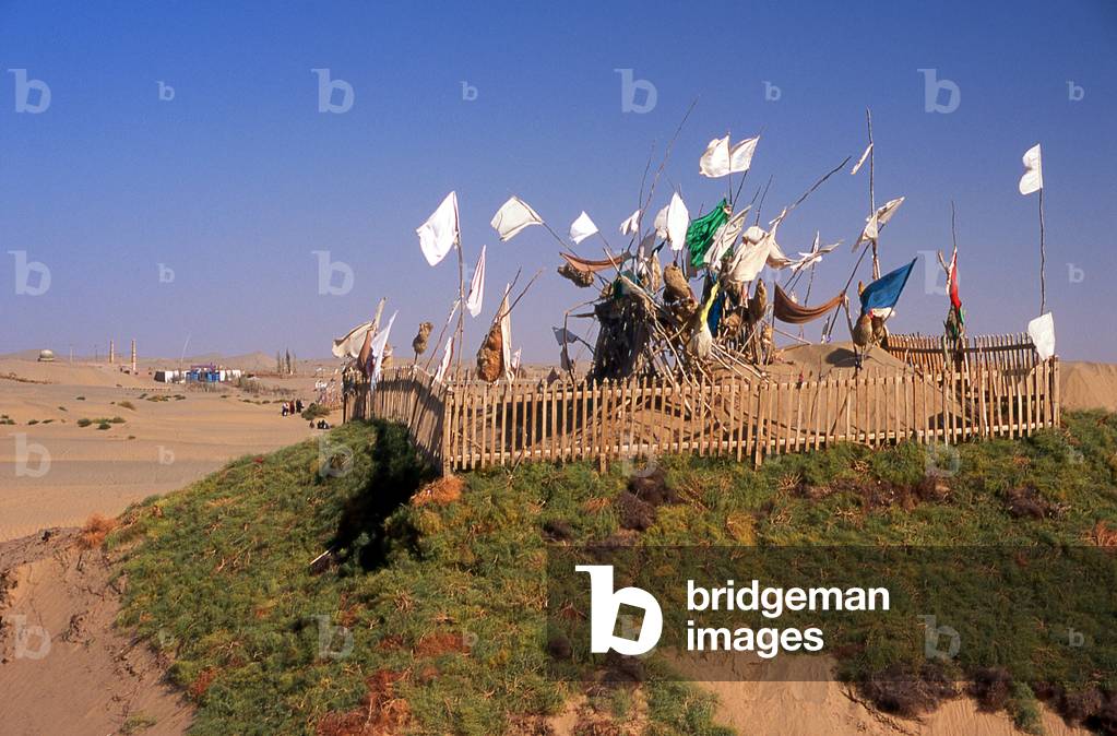 China: A tomb in the sand dunes near the Imam Asim Mazar (shrine in the background) in the desert near Khotan, Xinjiang Province