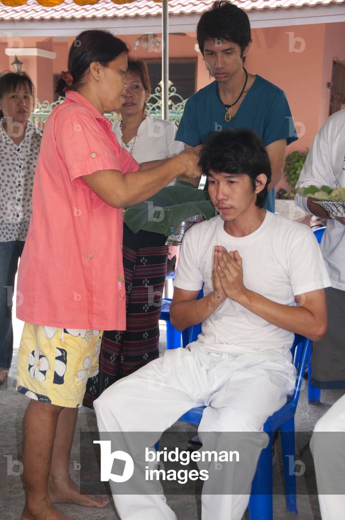 Thailand: Thai Buddhist ordination ceremony, Chiang Mai. Firstly the nakor monk-to-be has his head shaved. The first trimmings are made by parents, relatives or a senior monk