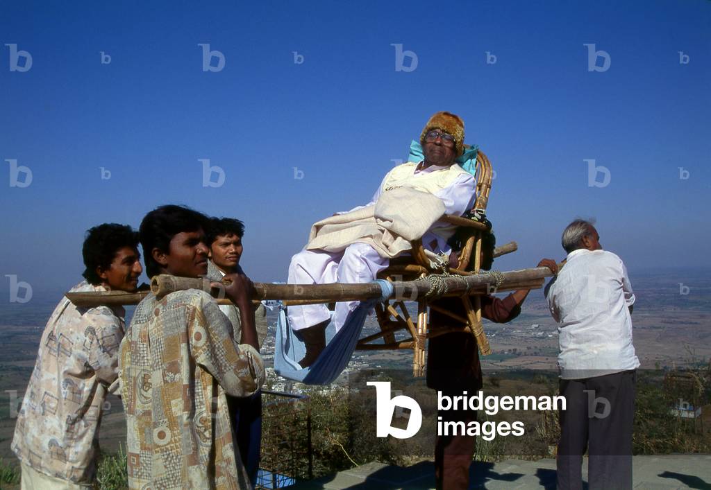 India: A pilgrim being carried in a sedan chair up to the holy Jain Palitana temples (11th to 16th Century CE) in the Shatrunjaya Hills, Gujarat (2004)