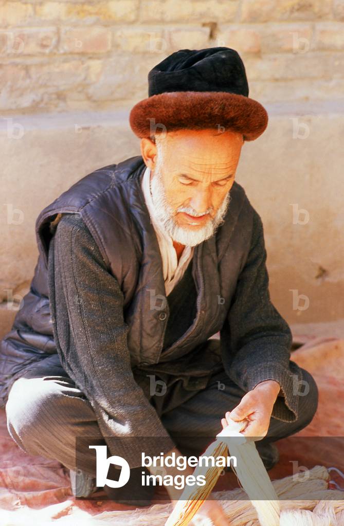China: A Uighur man sorting raw silk threads, Atlas Silk Workshop (Atlas Karakhana) in Jiya Village, about 13km northeast of Khotan, Xinjiang Province
