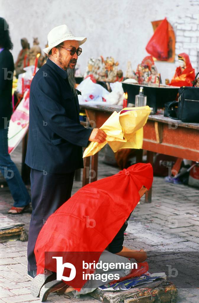 China: Taoist medium, Dayun Si (Dayun Temple), a Tang Dynasty (618 - 907 CE) era Taoist temple, Wuwei, Gansu Province. Taoist rites are performed, with mediums covering supplicants with red cloths, ringing bells and shaking censers