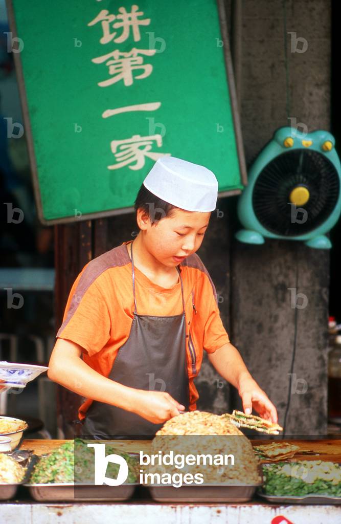 China: A young Hui Muslim serves street food in Xi'an's Muslim Quarter, Shaanxi Province