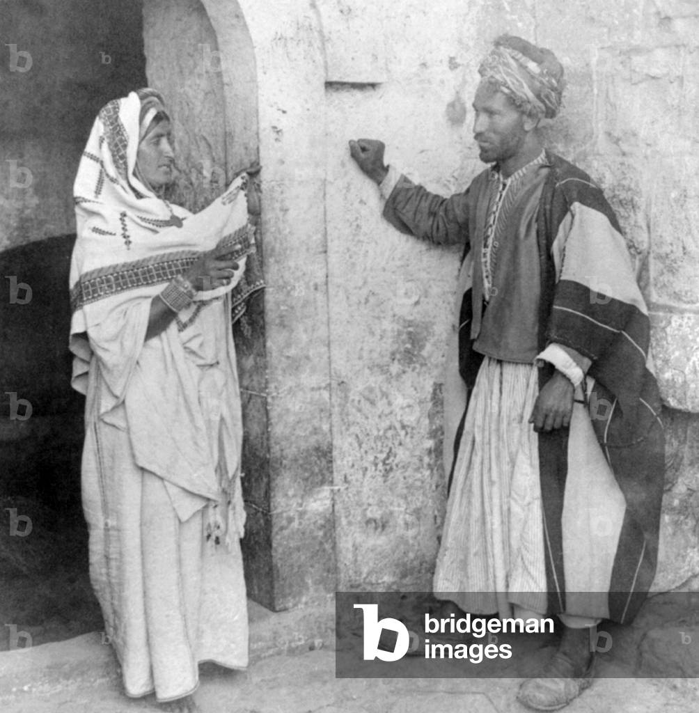 Palestine: A Palestinian man and woman posing in a doorway, c. 1900