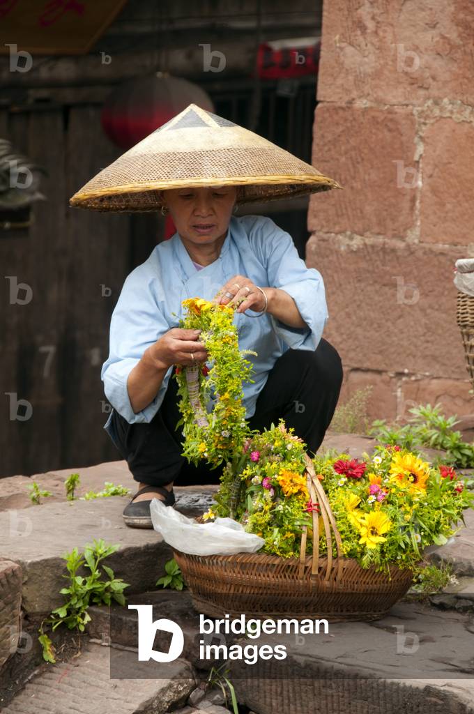 China: Tujia woman selling flower tiaras at the North Gate Tower, Fenghuang, Hunan Province
