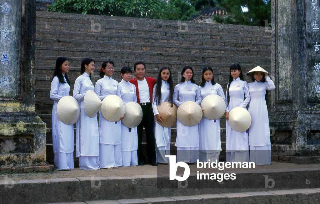 Vietnam: Students in traditional Vietnamese ao dai ('long dress') and non la (conical hat) at the Thien Mu Pagoda with Elvis Phuong, Hue