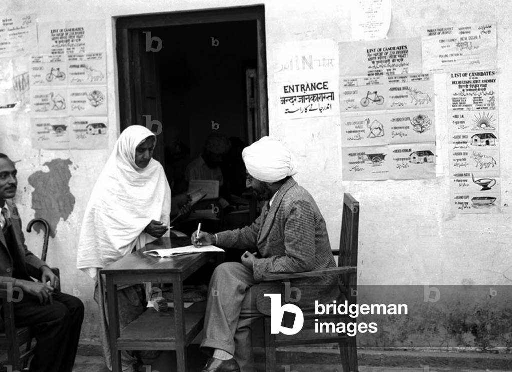India: First Lok Sabha general election, Delhi, January 1952. A female refugee being given her ballot papers after identification at a Polling Station in Lajpat Nagar