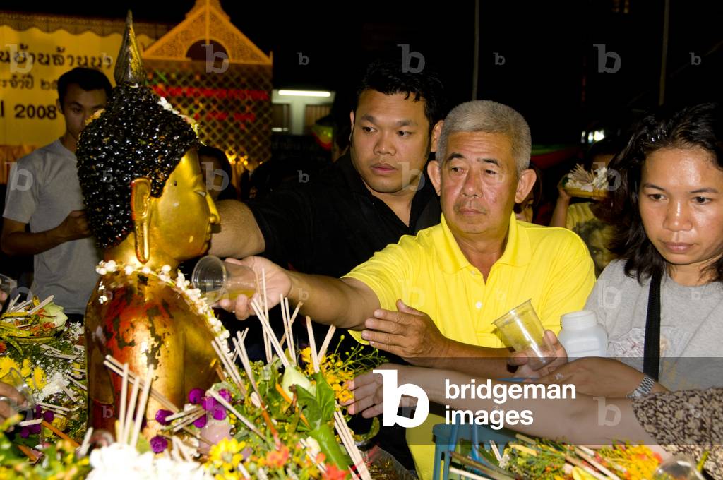 Thailand: Devotees pouring scented water over a Buddha image at the Inthakin or Lak Mueang Festival, Wat Chedi Luang, Chiang Mai