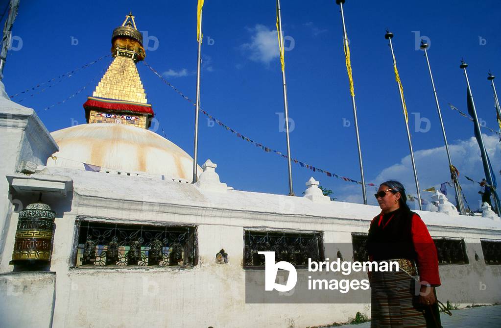 Nepal: Tibetan woman below the all seeing eyes of the great dome of Bodhnath stupa, Kathmandu