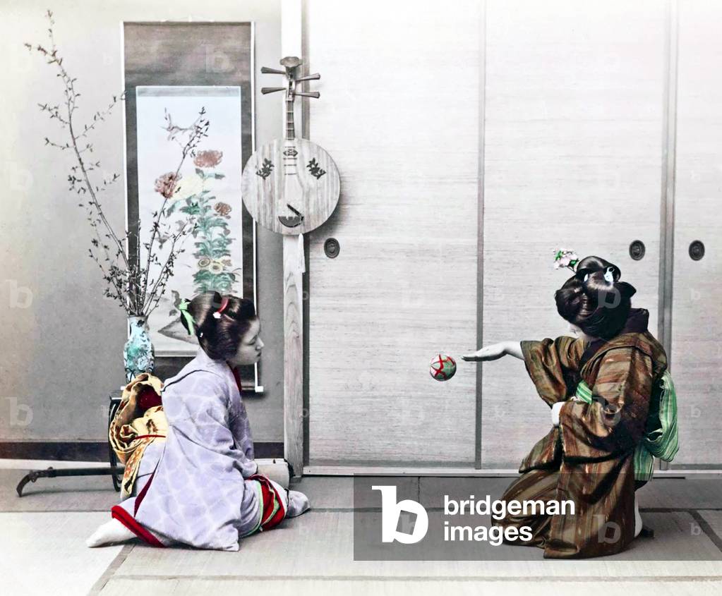 Japan: Studio portrait of two young Japanese women playing with a temari hand ball, 1890s