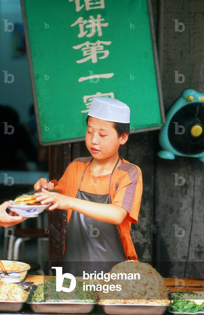 China: A young Hui Muslim serves street food in Xi'an's Muslim Quarter, Shaanxi Province