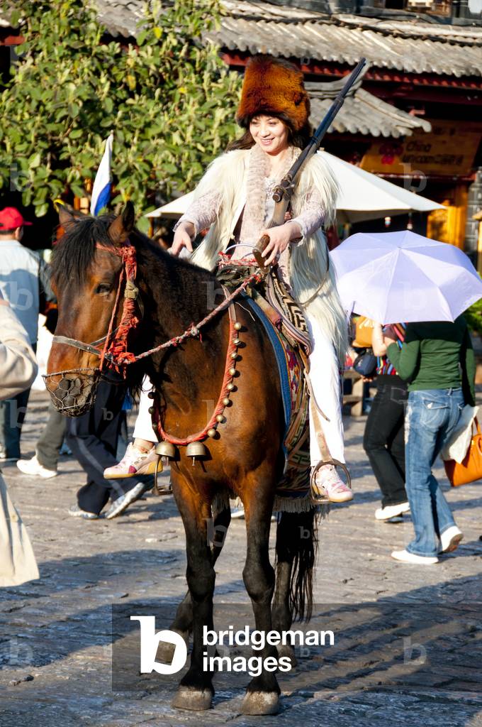 China: Tourist dressed as Naxi hunter, Old Market Square (Sifang Jie), Lijiang Old Town, Yunnan Province