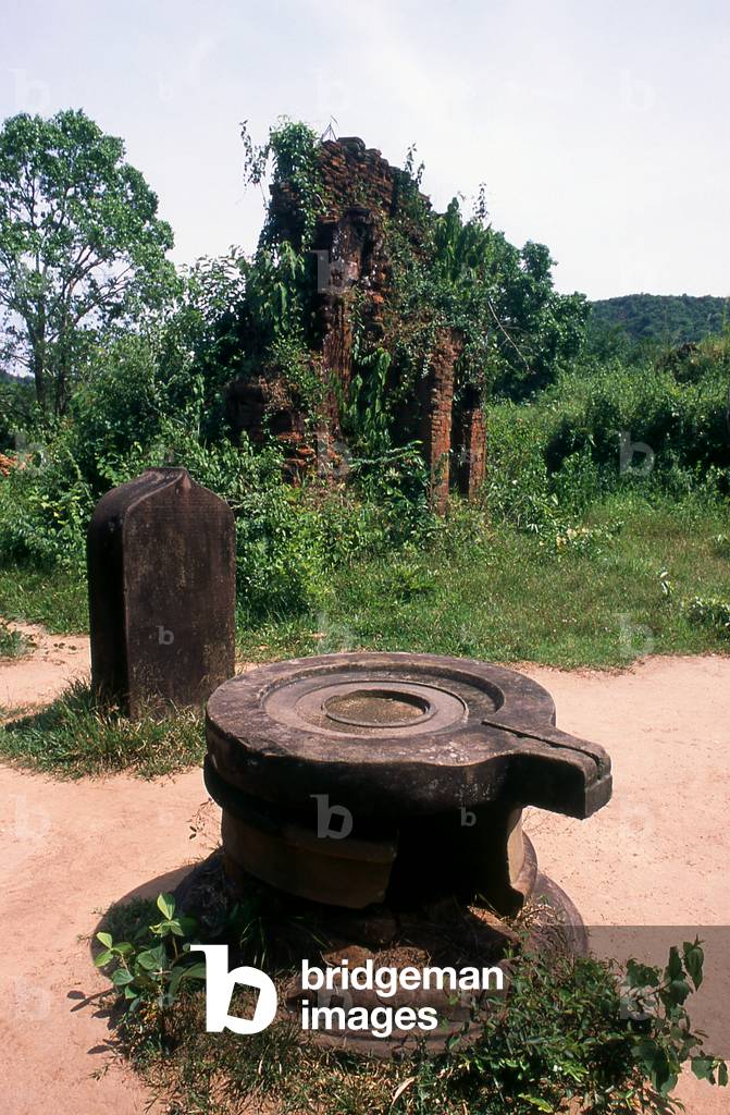 Vietnam: Yoni (symbol of the Goddess Shakti or Devi) with a stele and Cham temple tower in the background (7th - 8th century), My Son, Quang Nam Province