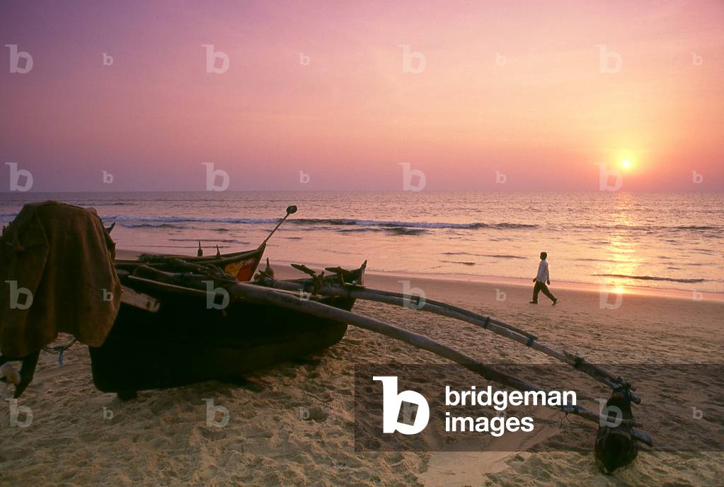 India: A traditional Goan outrigger fishing boat sits on the beach at Calangute Beach, North Goa