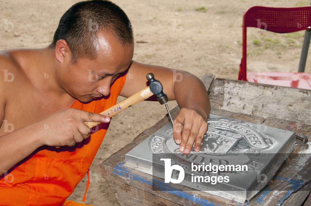 Thailand: Monk working on a silver Manchester United shield, Wat Meun San, Chiang Mai, northern Thailand