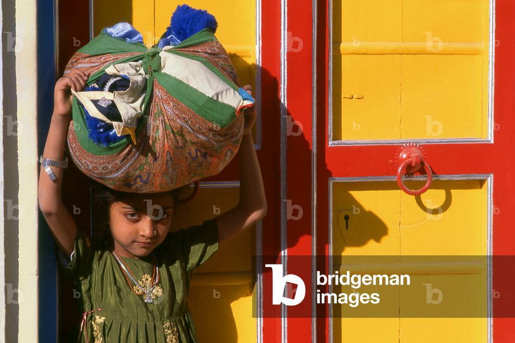 India: A young girl in front of a brightly-painted door at a Hindu temple in Kutch, Gujarat State
