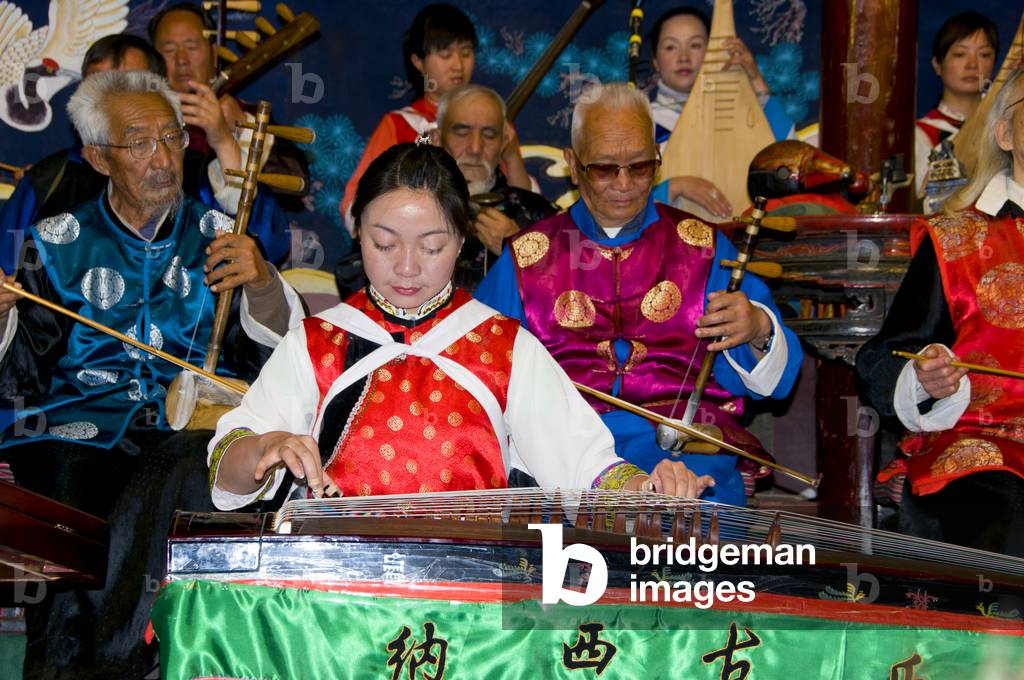 China: A woman plucks a guzheng, the Naxi (Nakhi) Folk Orchestra, Naxi Orchestra Hall, Lijiang Old Town, Yunnan Province