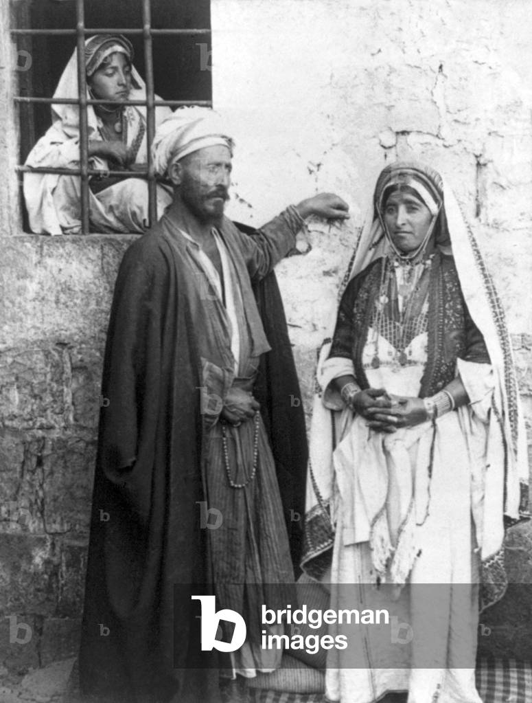 Palestine: 'The shaykh and his wife'. Perhaps the woman in the barred window is their daughter. c. 1900