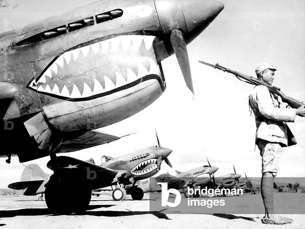 China: A Chinese KMT soldier guards a line of American P-40 fighter planes, painted with the shark-face emblem of the `Flying Tigers,' SW China, 1942