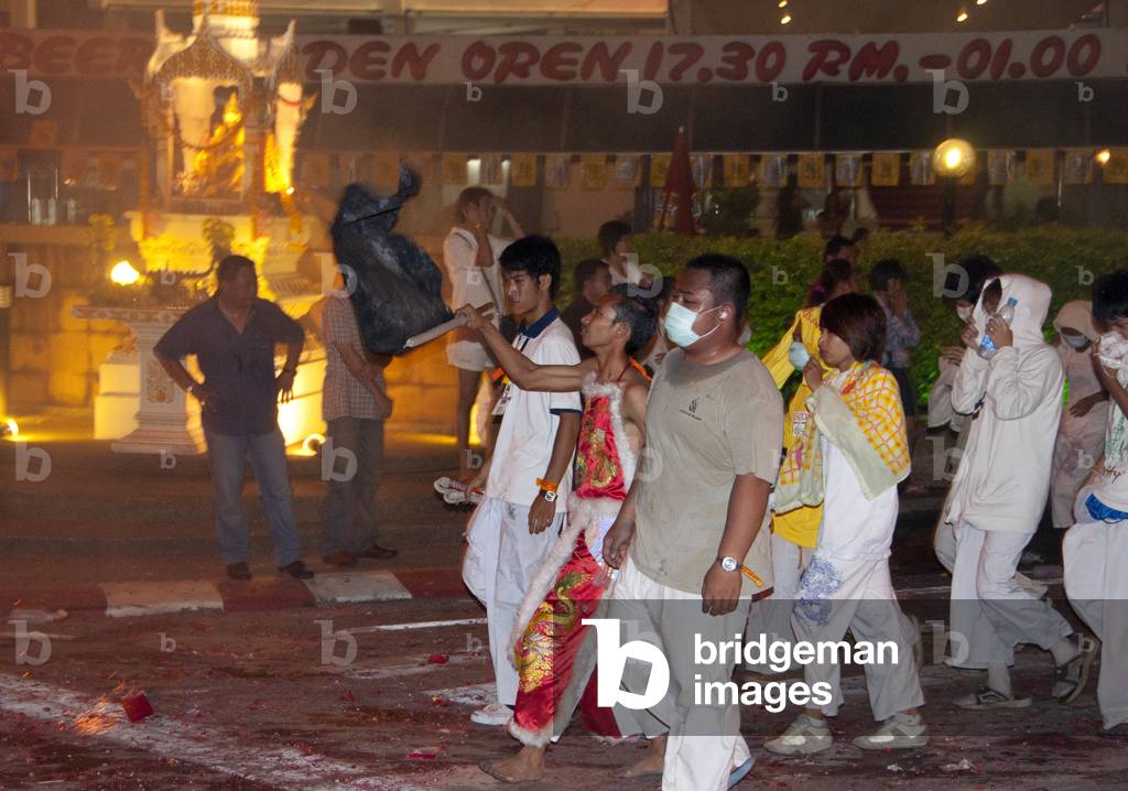Thailand: An entranced devotee or 'Ma Song' waves a flag in the night parade, Phuket Vegetarian Festival