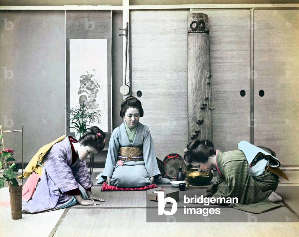 Japan: Studio portrait of two young women greeting a third and presenting her with a gift box, 1890s