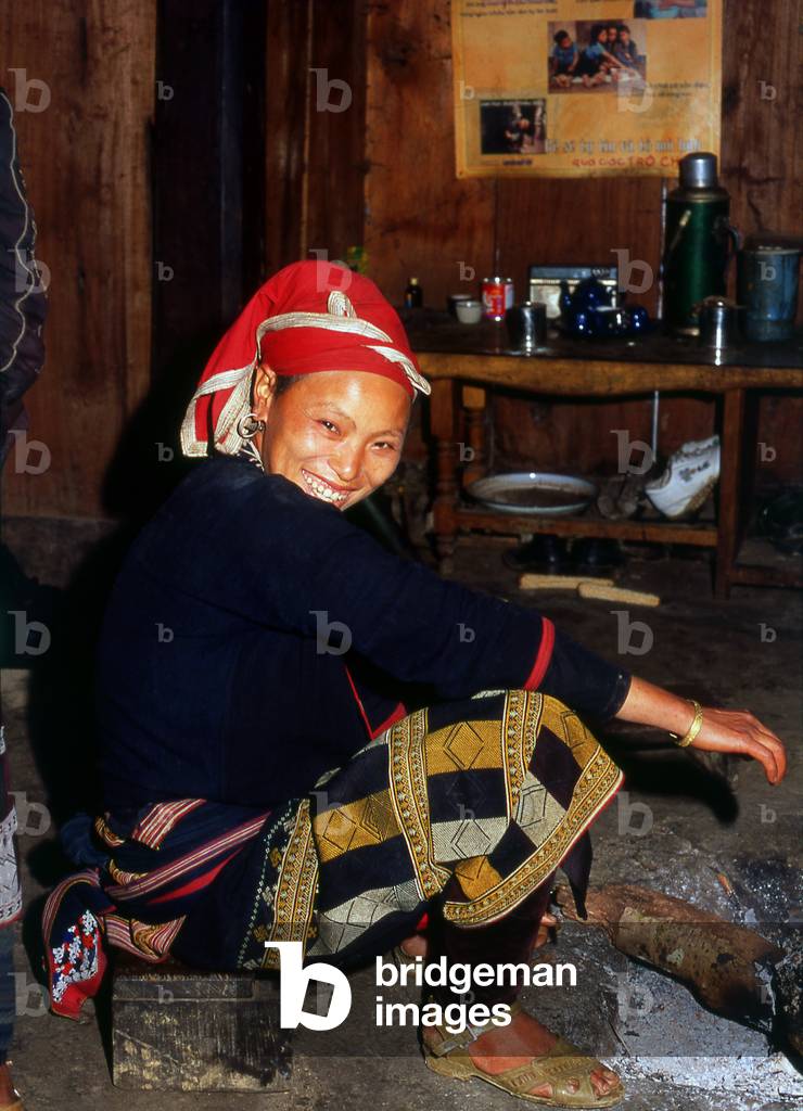 Vietnam: Red Dao (Zao) woman sits next to a fire on a cold day in the mountains, Tha Phin village, near Sapa