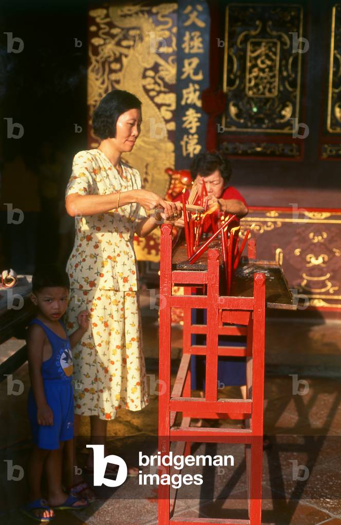 Malaysia: A Chinese mother lights incense while her son looks on at the Cheng Hoon Teng Temple (Temple of Green Cloud), Malacca