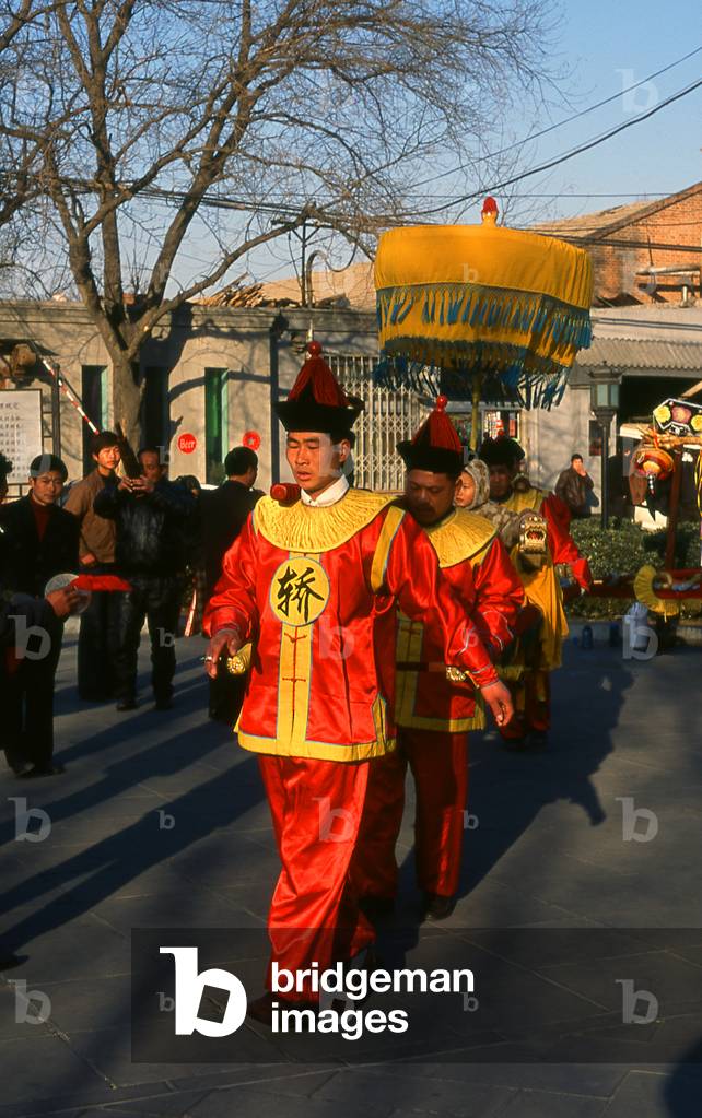 China: A child is paraded on an elaborately decorated palanquin in front of the Bell Tower (Zhonglou), Beijing