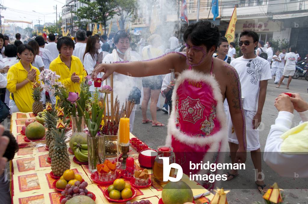 Thailand: Entranced devotee or 'Ma Song' visits a street altar set up by a shop owner looking for blessings from passing devotees, Phuket Town, Phuket Vegetarian Festival