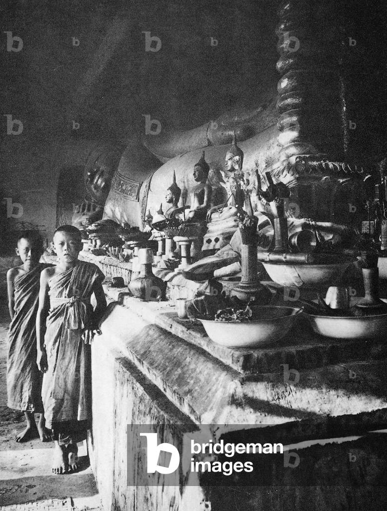 Thailand: Two novice monks stand next to a reclining Buddha, Wat Phra That Haripunchai, Lamphun (c. 1920)