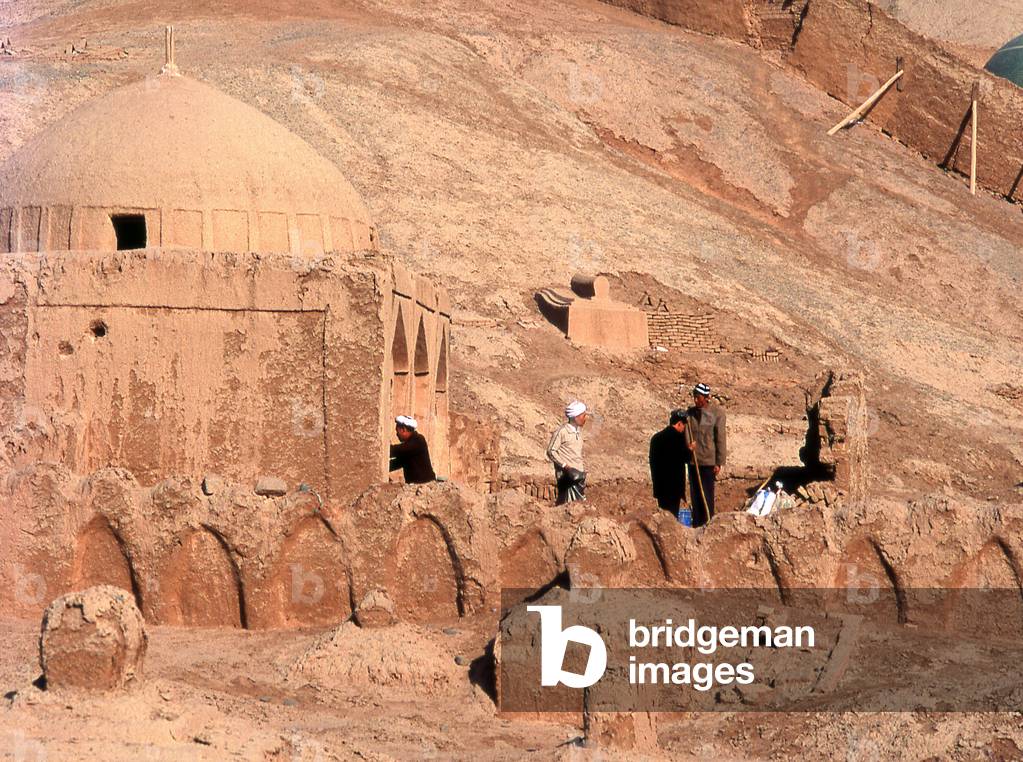 China: Men working on a tomb in the cemetery next to the village of Tuyoq near Turpan, Xinjiang Province